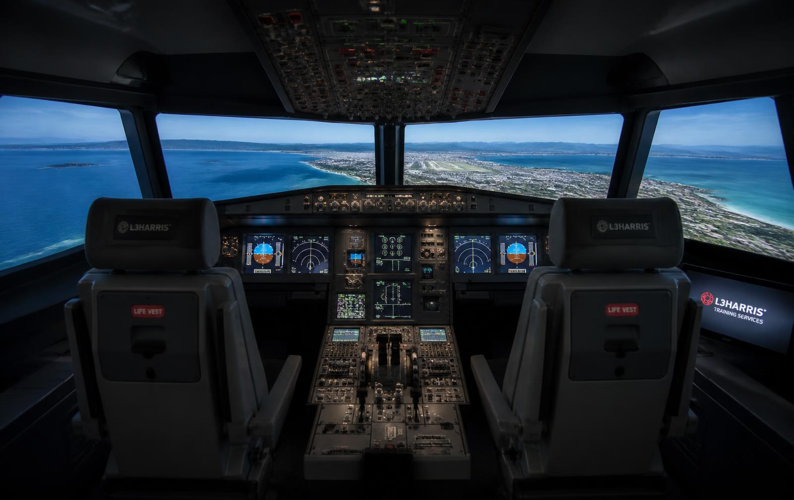 Professional flight simulator cockpit with a Mediterranean coastal approach on the visual display